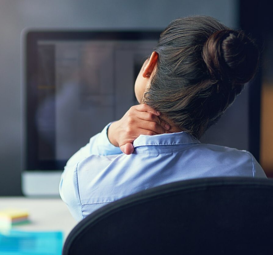 Rearview shot of a businesswoman suffering from neck pain at the office